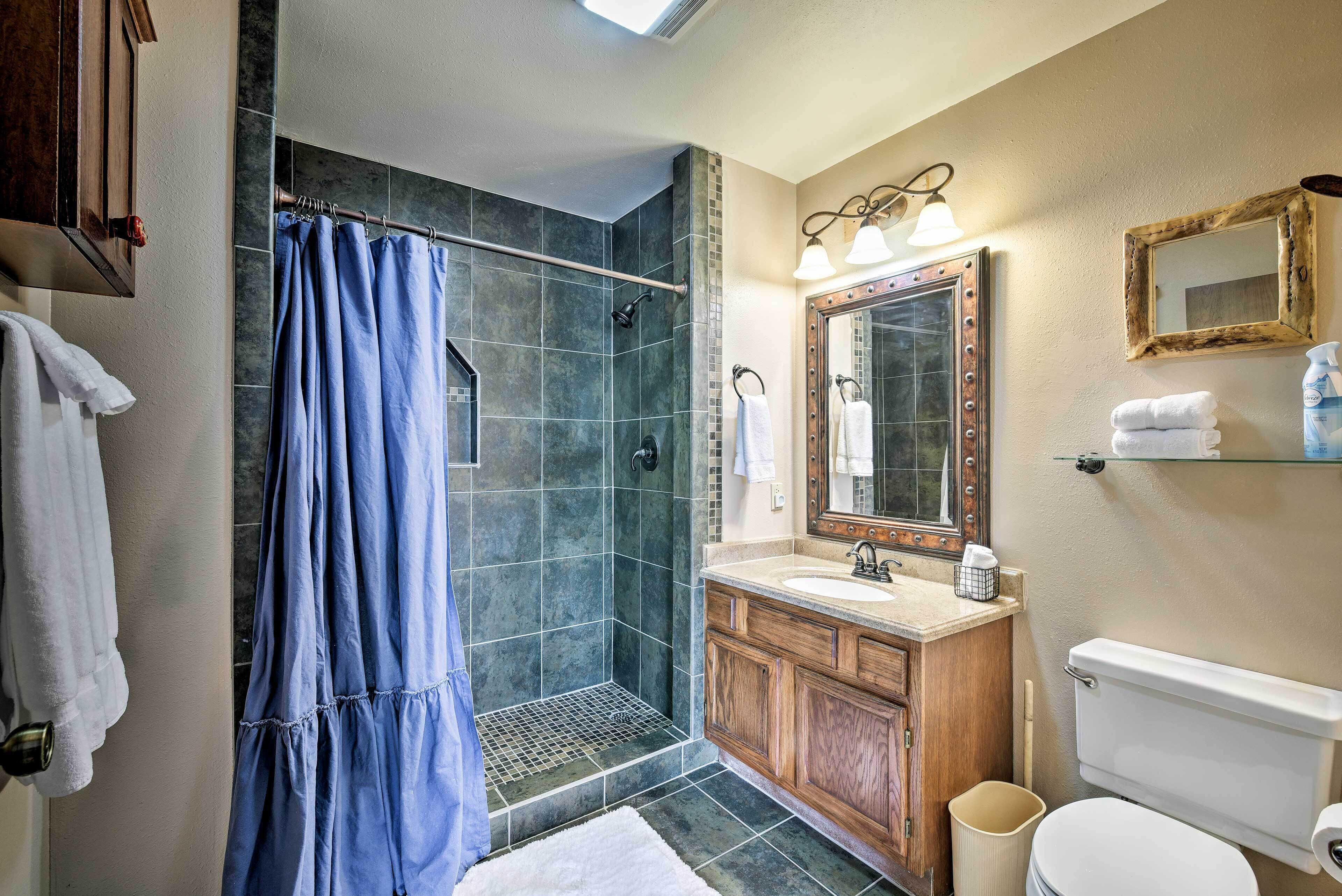 Ein Badezimmer mit Dusche, Waschbecken, Toilette und Spiegel.