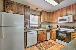 A kitchen with wooden cabinets, a white refrigerator, a microwave, a dishwasher, and an oven.