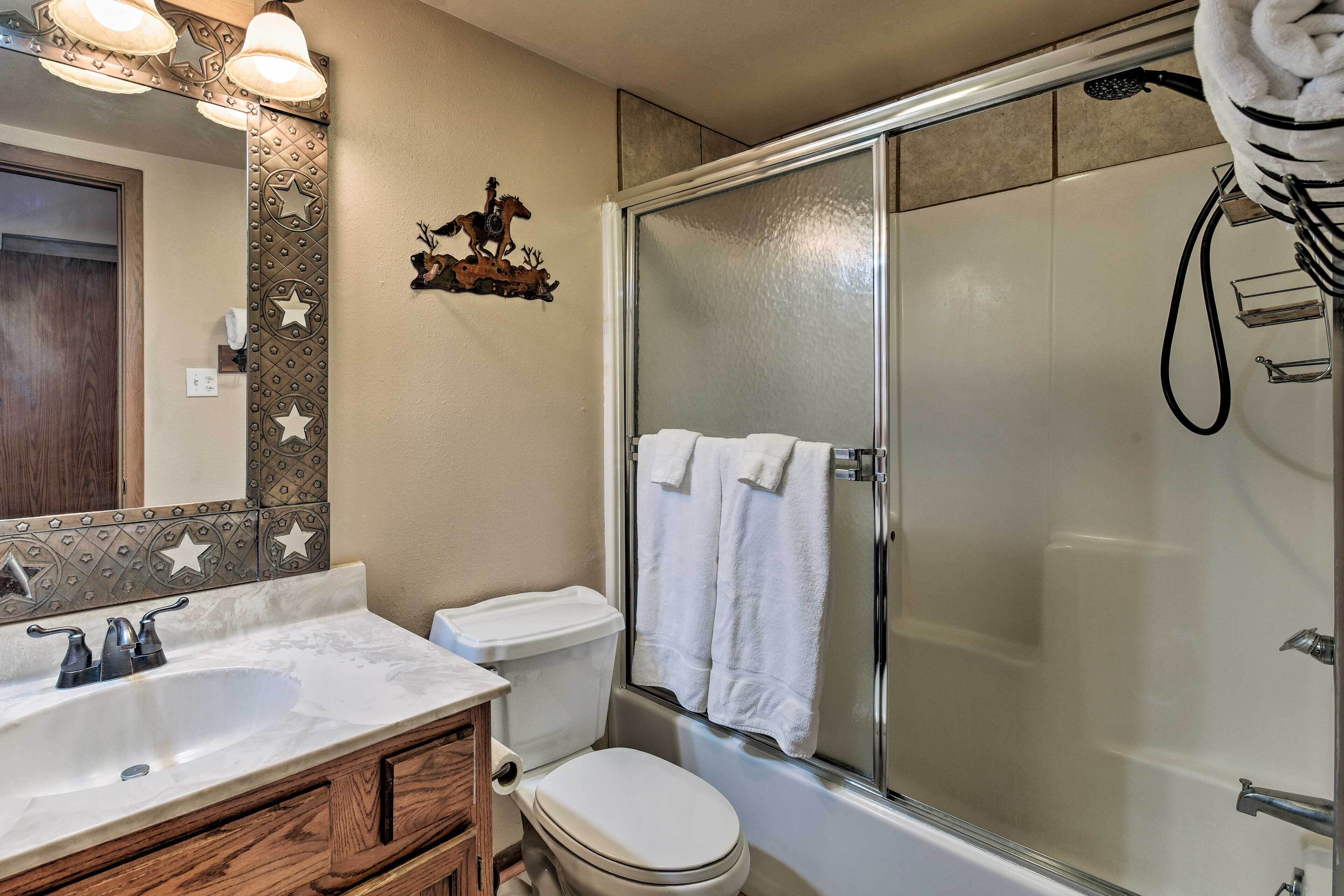 Baño con ducha, inodoro, lavamanos y un detalle decorativo en la pared con motivos de estrellas y una decoración de caballo.