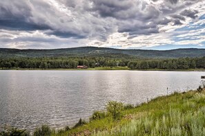 A lake with a forested hill in the background and a small building near the water's edge.