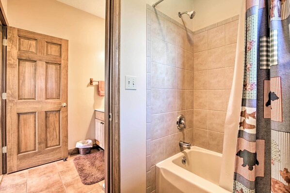 A bathroom with a bathtub, a shower, and a wooden door.