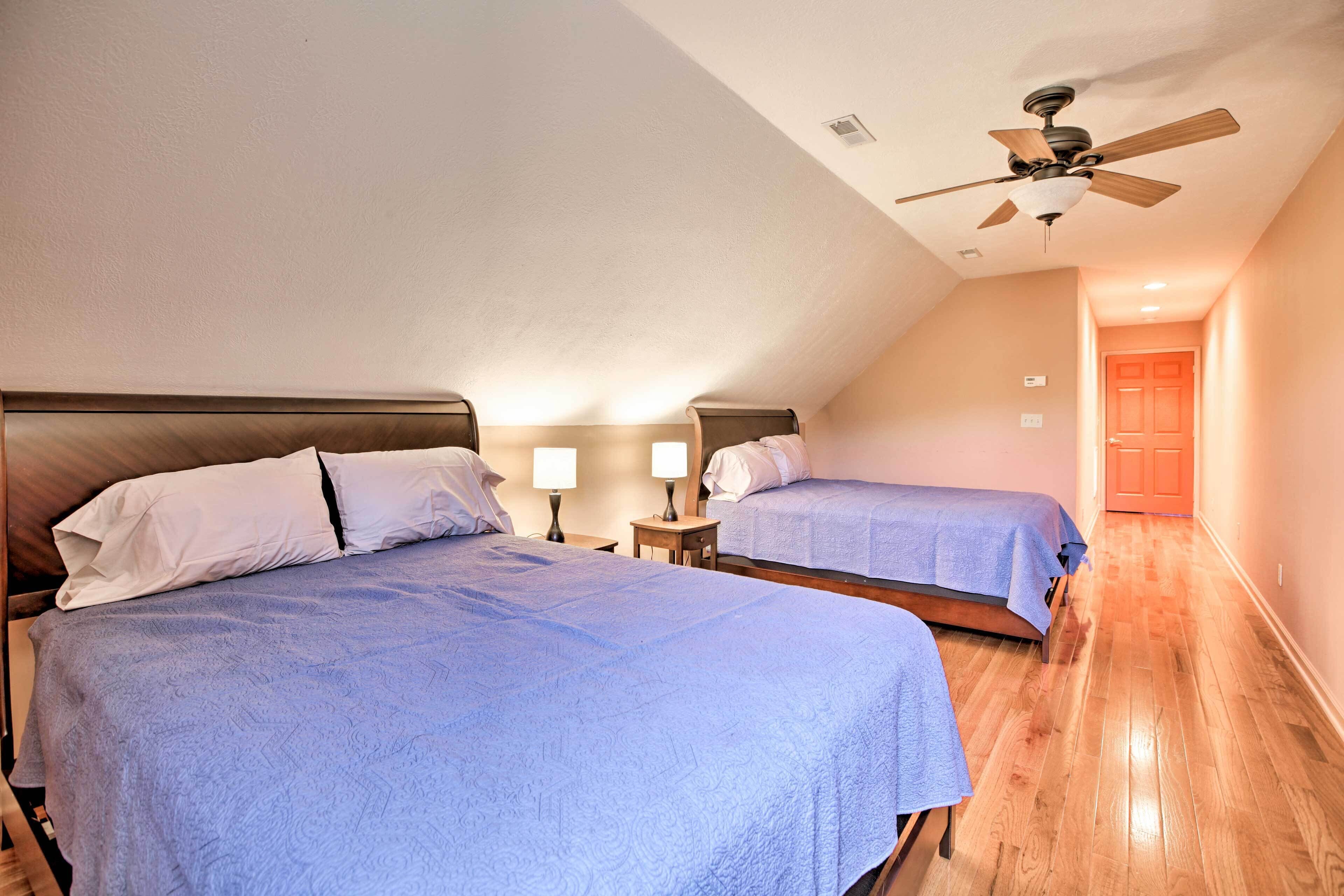 A hotel room with two beds, a ceiling fan, and a wooden floor.