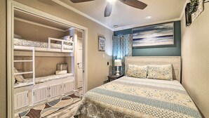 A bedroom with a bunk bed, a bed with patterned bedding, a ceiling fan, and a painting on the wall. - Updated Front Beach Condo w/ Resort Amenities! (Corpus Christi)