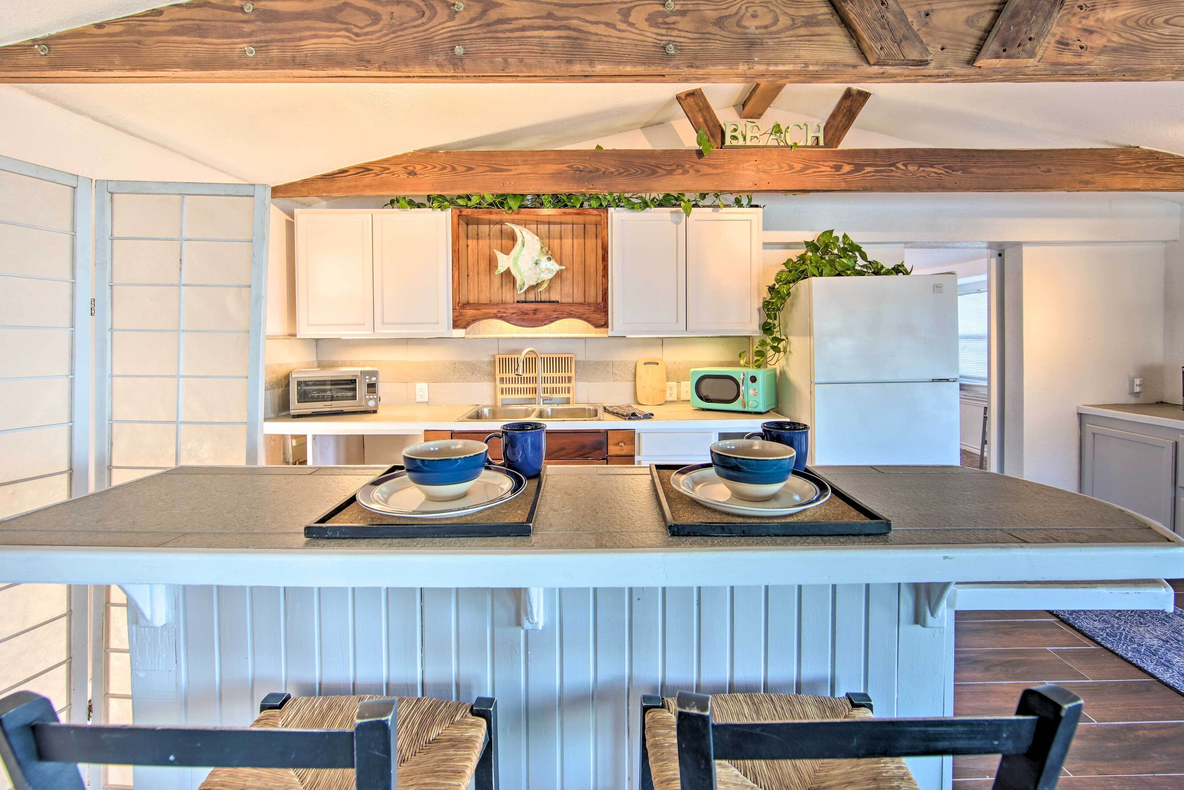 Una cocina con isla central, armarios blancos y techo de madera.
