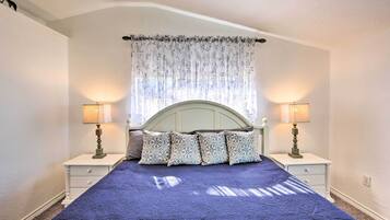 Un dormitorio con una cama grande, dos mesitas de noche con lámparas y una cortina con motivos florales.