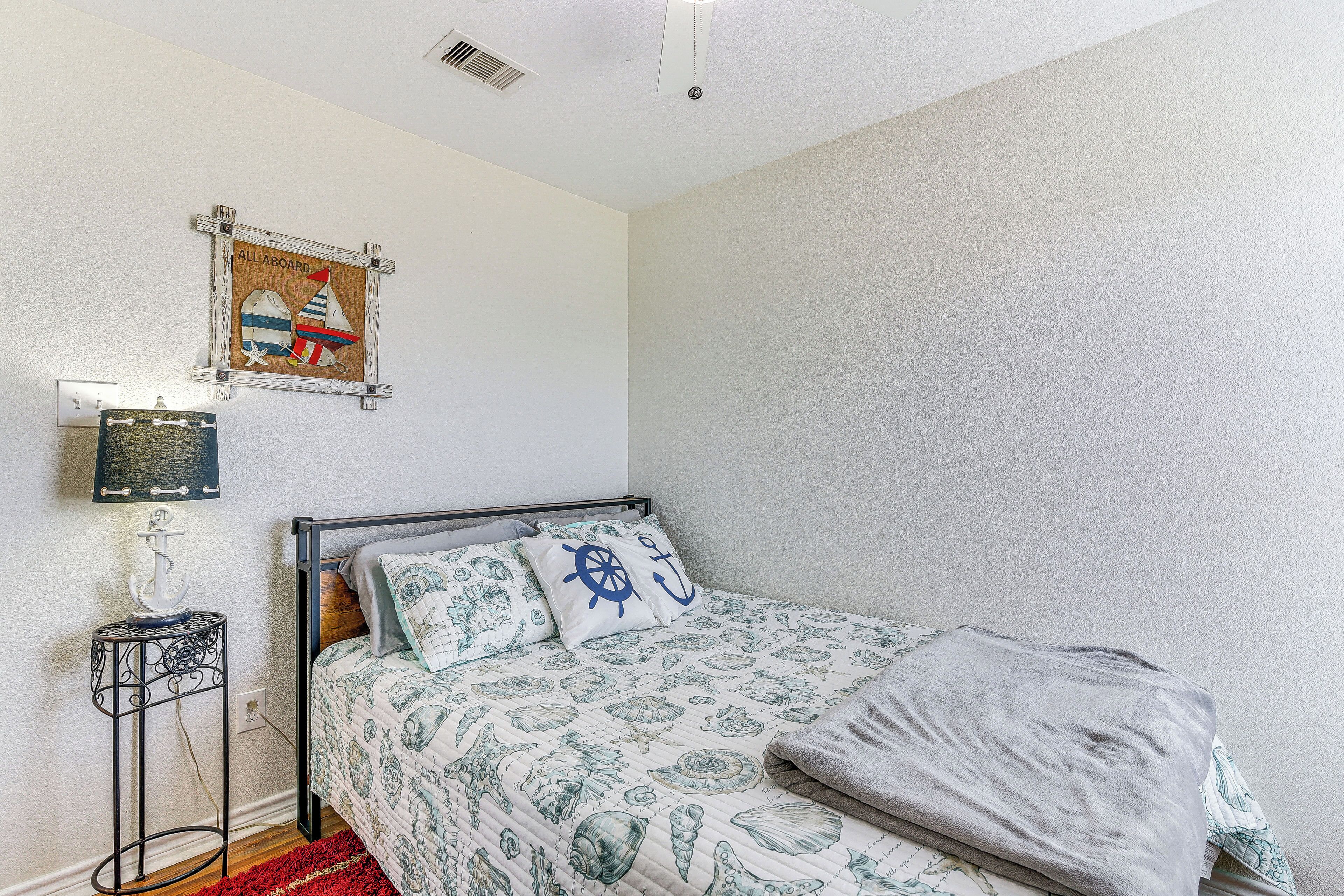 A bedroom with a bed, a wall-mounted shelf, and a poster.