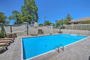 Ein rechteckiger Swimmingpool mit klarem, blauem Wasser, umgeben von einer Betonplattform, Holzliegen und einer kleinen Treppe zu einem überdachten Bereich.