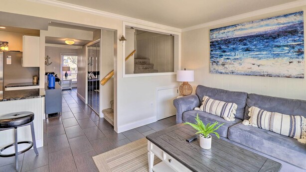 Ein modernes Wohnzimmer mit einem grauen Sofa, einem Couchtisch und einem Gemälde mit Strandmotiv.