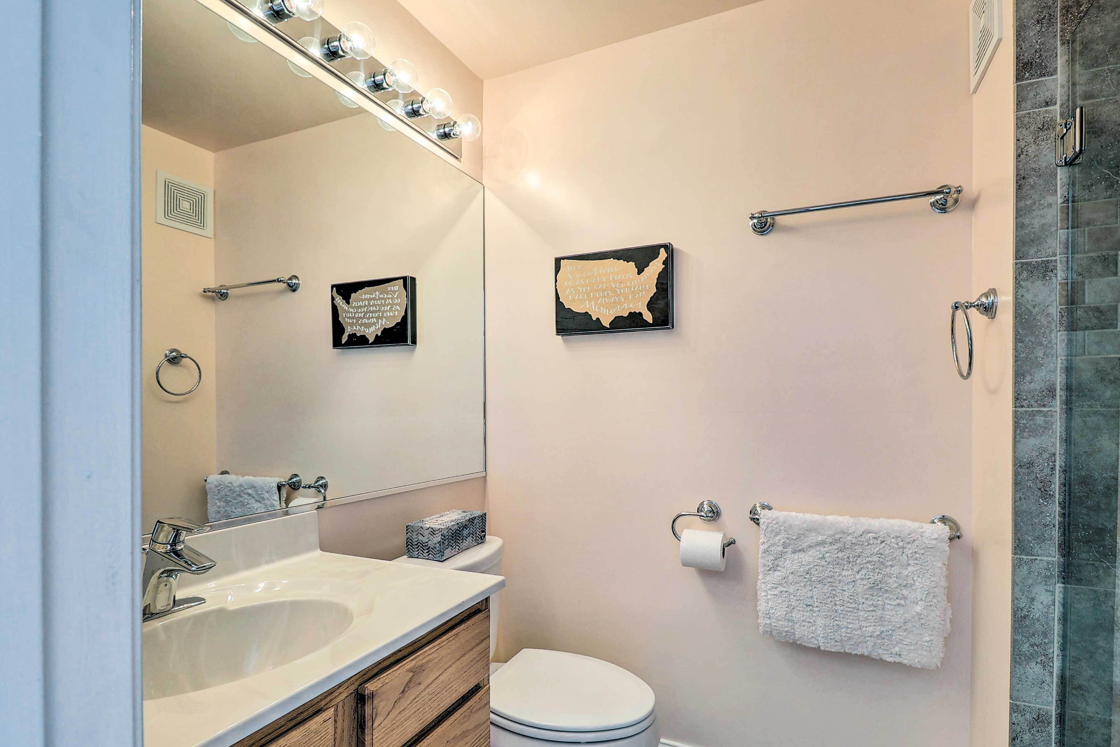A bathroom with a large mirror, a sink, a toilet, and a shower area.