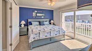 Ein Schlafzimmer mit Bett, Nachttischen, Deckenventilator und Blick ins Freie.