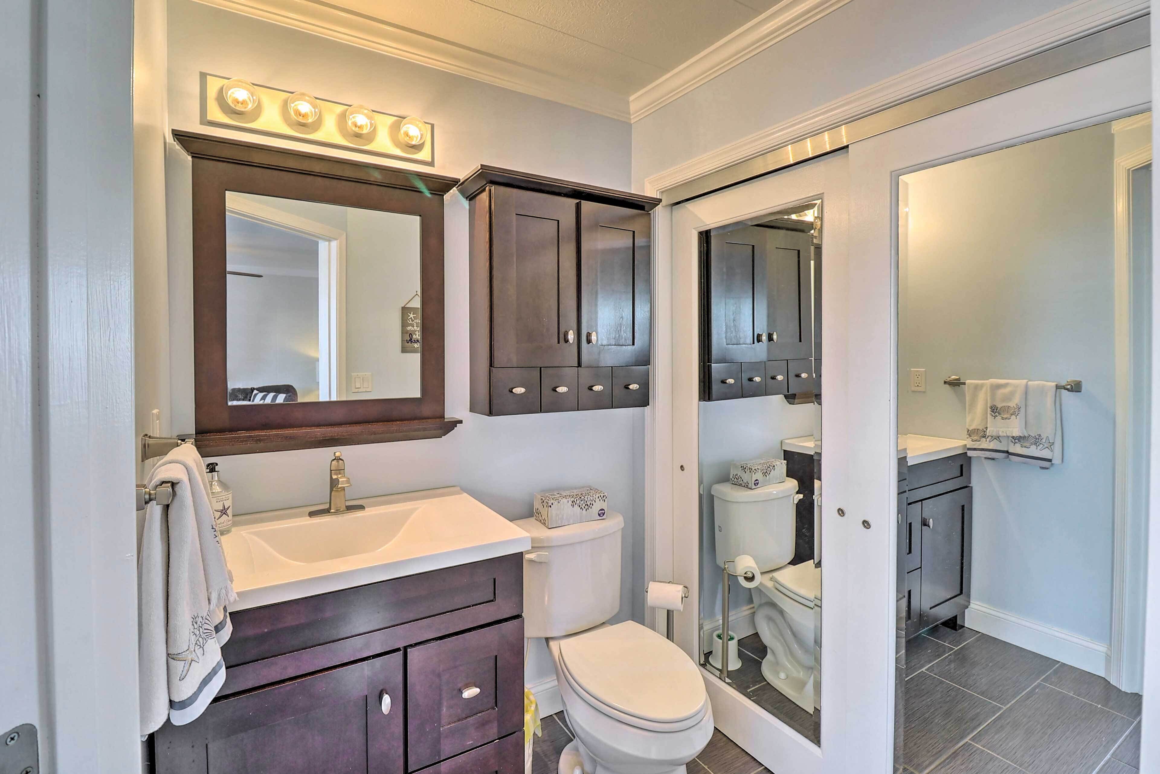 A bathroom with a vanity, a toilet, and a shower area.