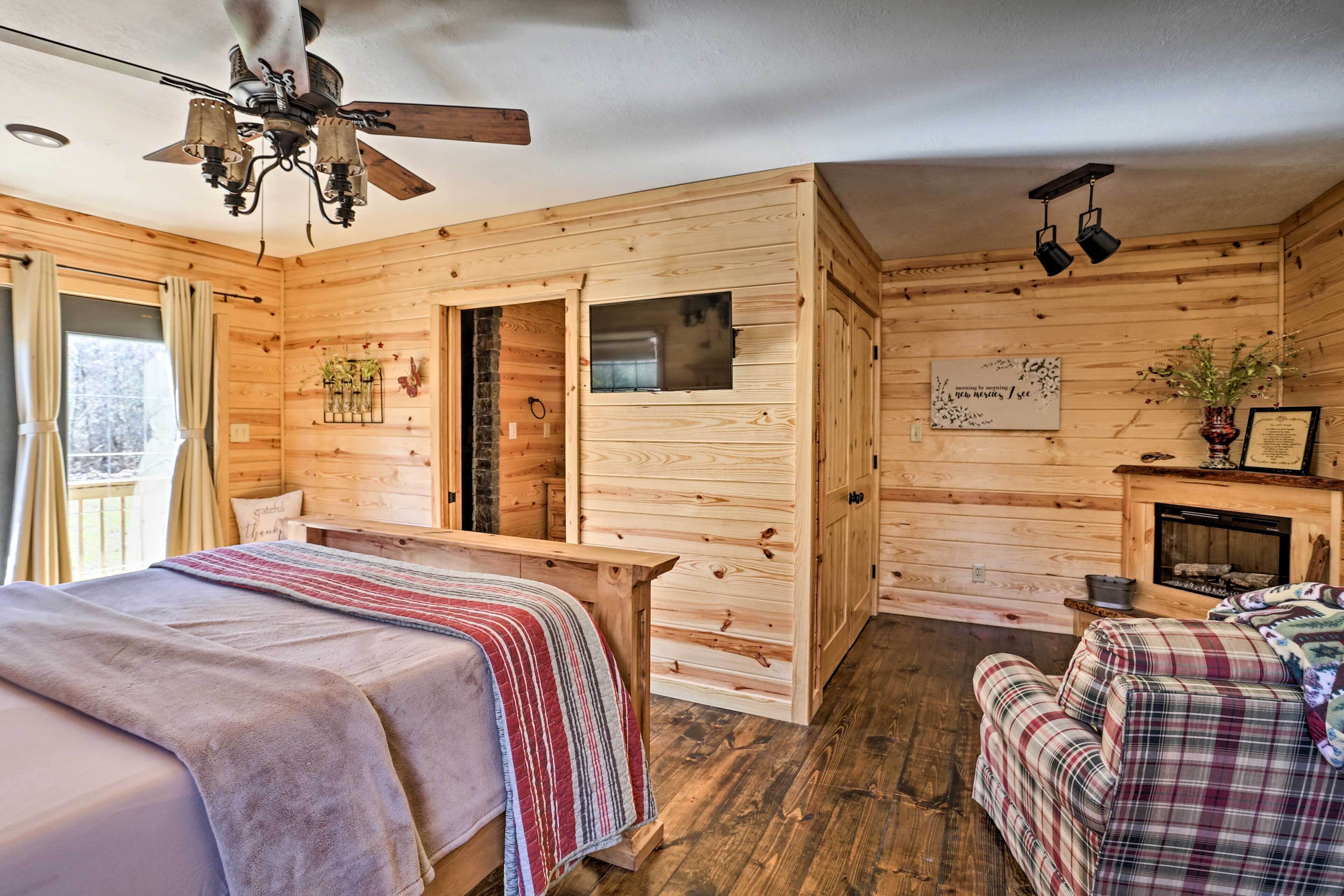 Una habitación acogedora de cabaña de madera con una cama, un banco, una chimenea y un ventilador de techo.