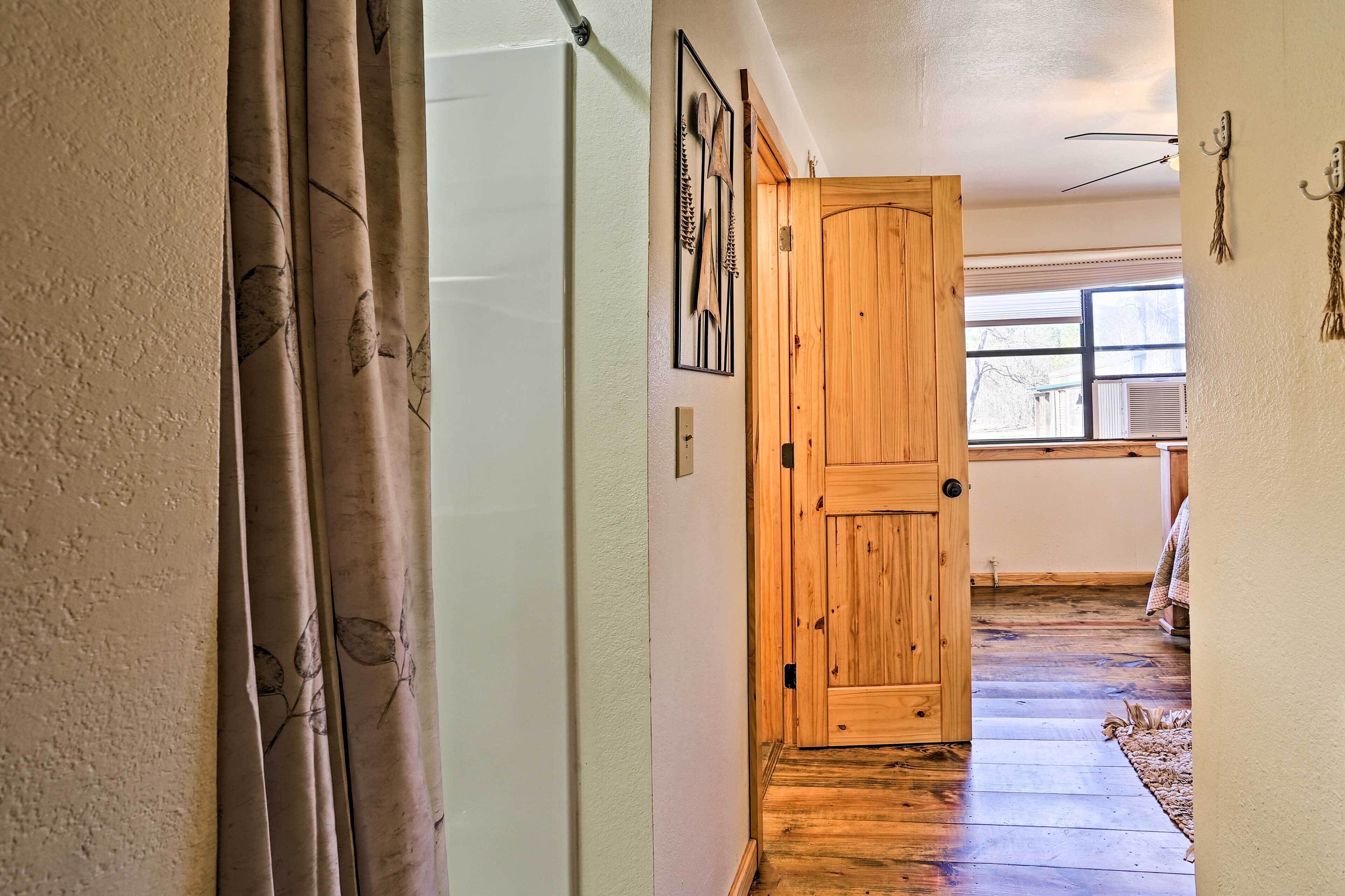 A hallway with a wooden door, a window, and a doorbell.