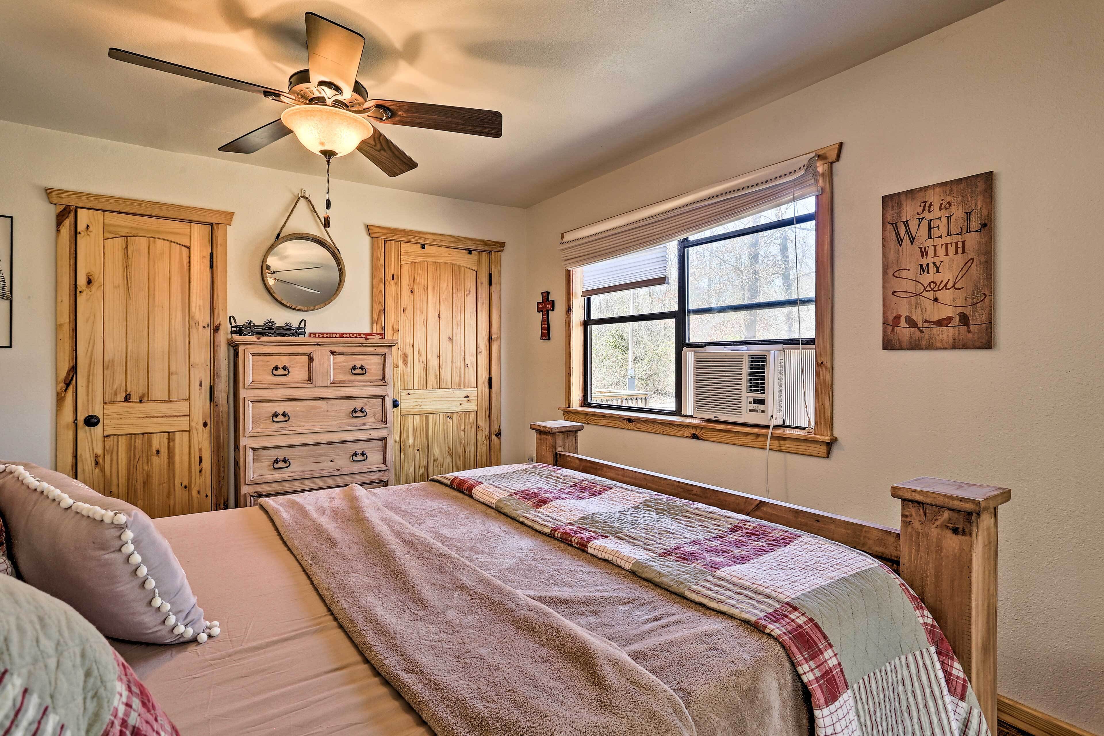 A bedroom with a bed, a dresser, a mirror, a ceiling fan, and a window with blinds.