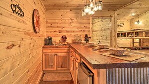 A wooden cabin interior with a kitchen area featuring a wooden countertop, a refrigerator, and a sign that reads "All the fun in the cabin." - Serene Cabins w/ Decks & 8 Acres on Kiamichi River (Hodgen)