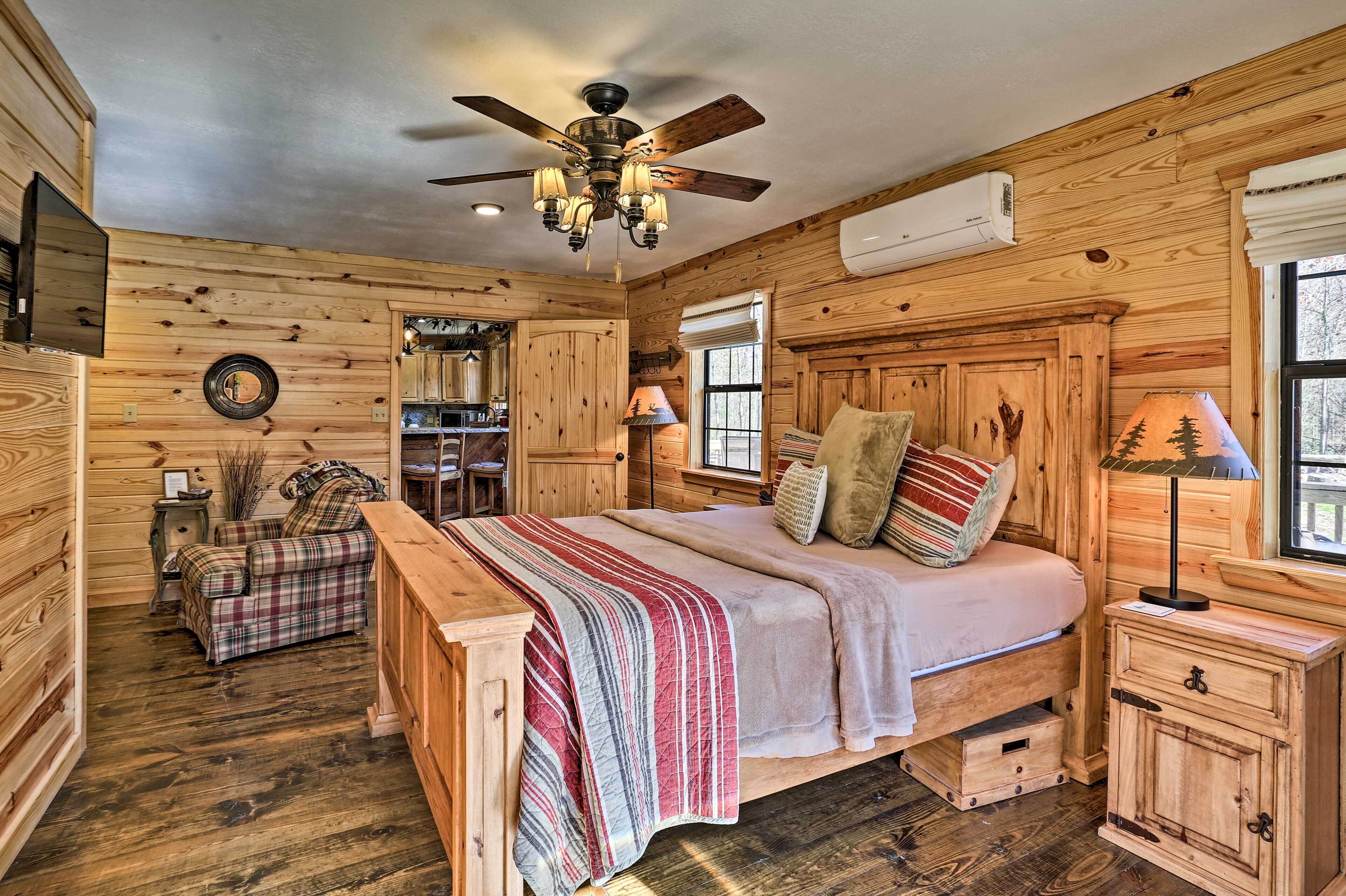 A wooden cabin-style bedroom with a bed, a ceiling fan, a window, and a wooden dresser.