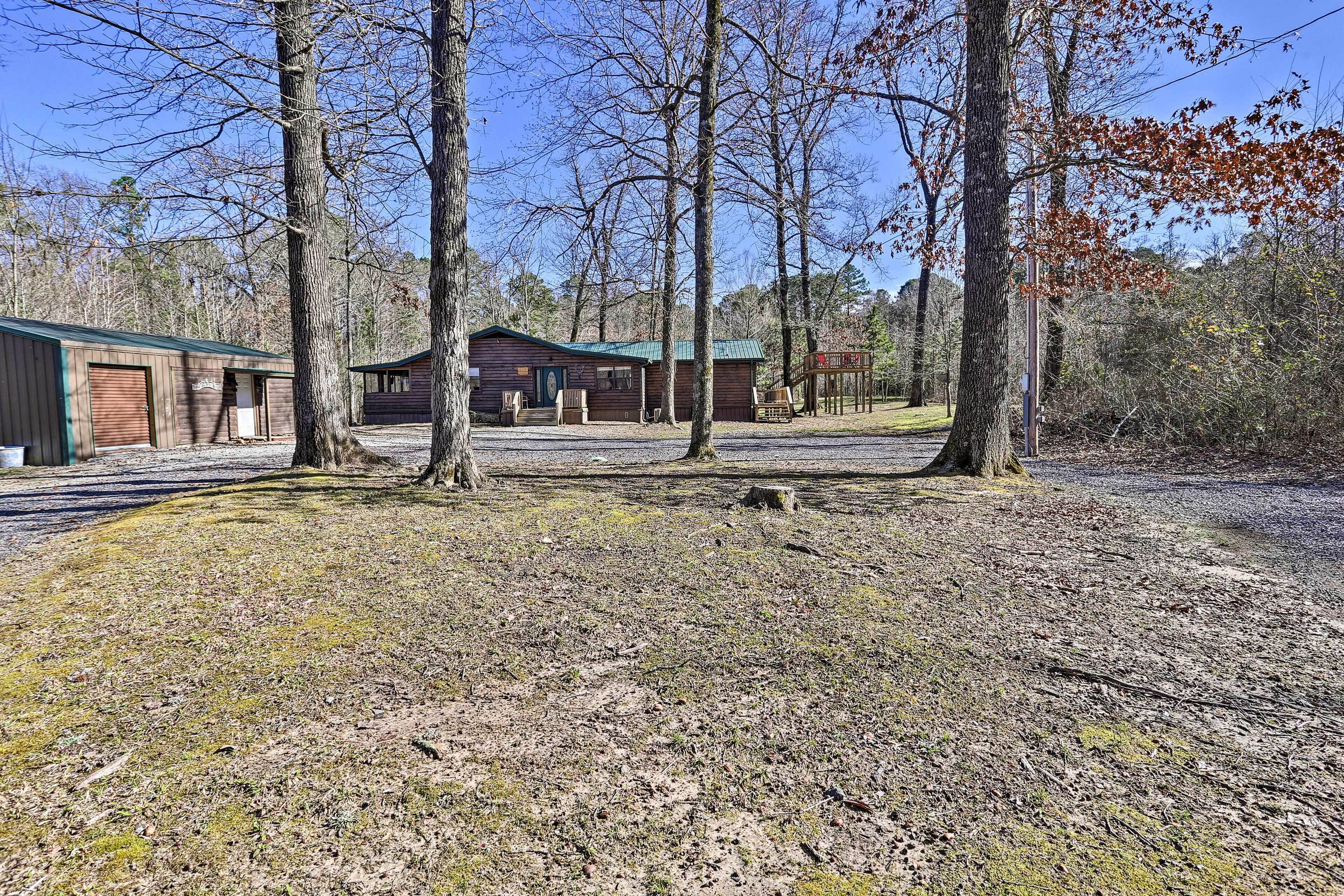 Un chalet rustique avec un toit végétalisé, entouré d’arbres et bordé d’une allée en gravier.