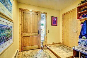 A wooden door with a mat at the entrance, a framed picture on the wall, and a shelf with items on the right. - Beautiful Remodeled Mountain Home in Deer Valley! (Park City)