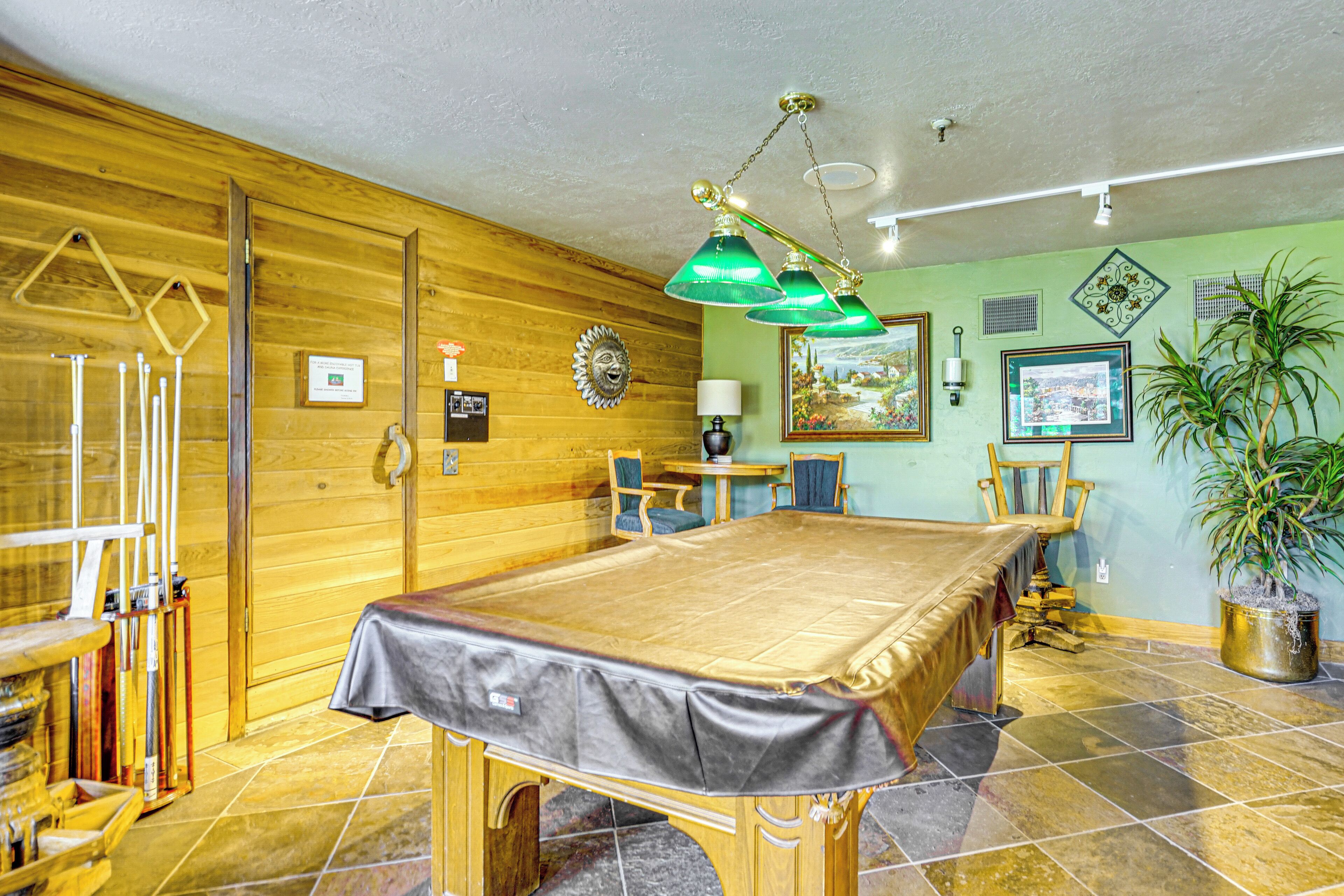 Een houten kamer met een pooltafel, stoelen, een lamp en een potplant.