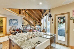 A kitchen with a marble countertop, wooden ceiling beams, and a view of the dining area. - Beautiful Remodeled Mountain Home in Deer Valley! (Park City)
