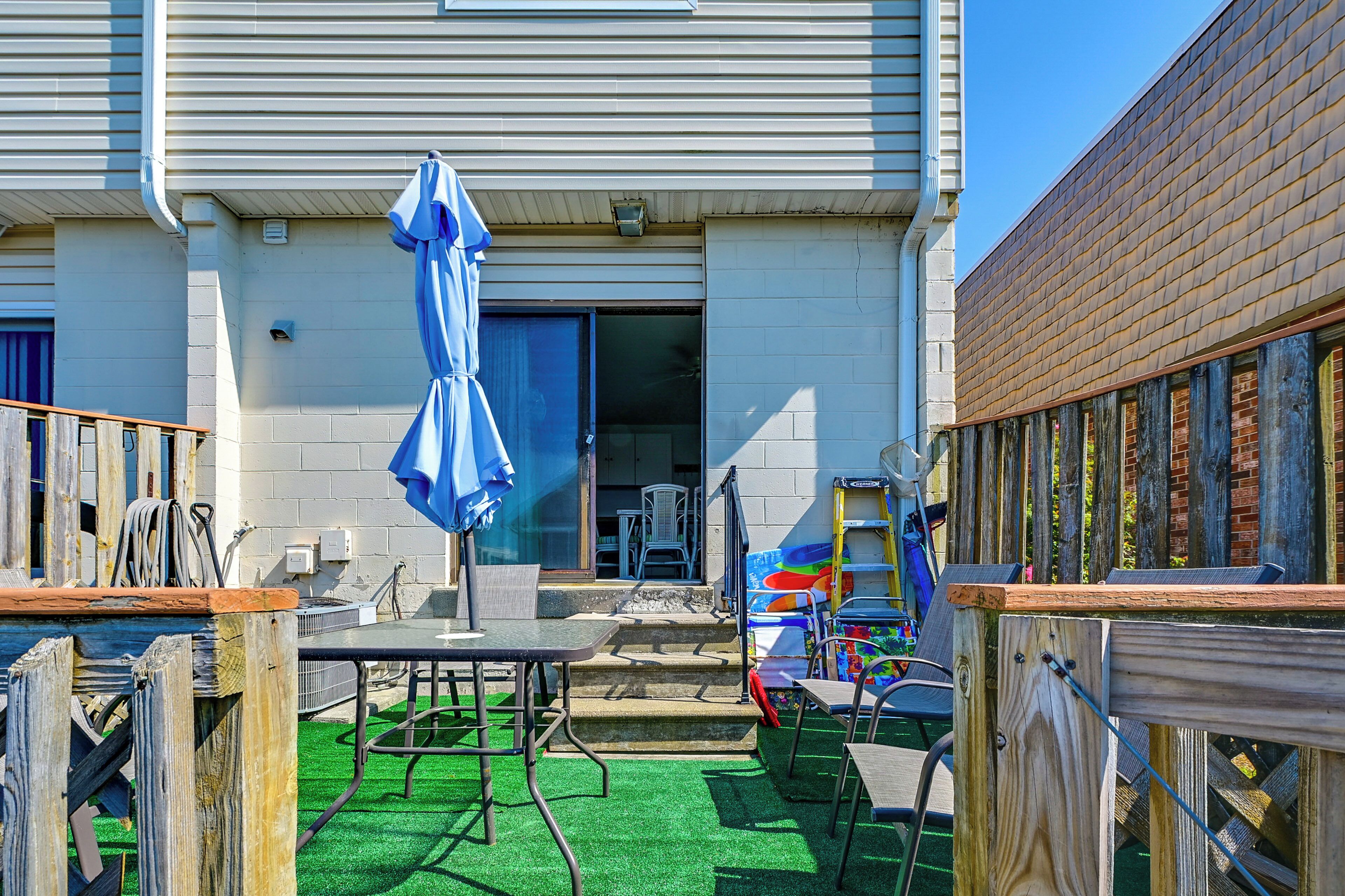 A patio area with outdoor furniture, a blue umbrella, and a building with a brick facade.