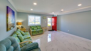 A spacious living area with a sofa, a small table, and a red door.