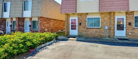A row of townhouses with brick and siding exteriors, front doors, and small front yards.
