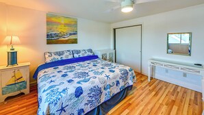 A bedroom with a bed, a ceiling fan, a painting, a nightstand, and a dresser.