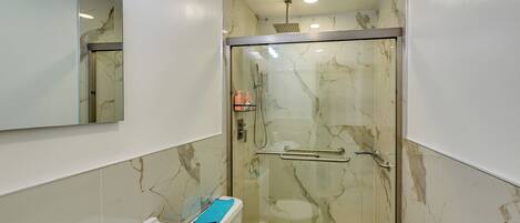 A bathroom with a glass-enclosed shower, a white sink, and a toilet.