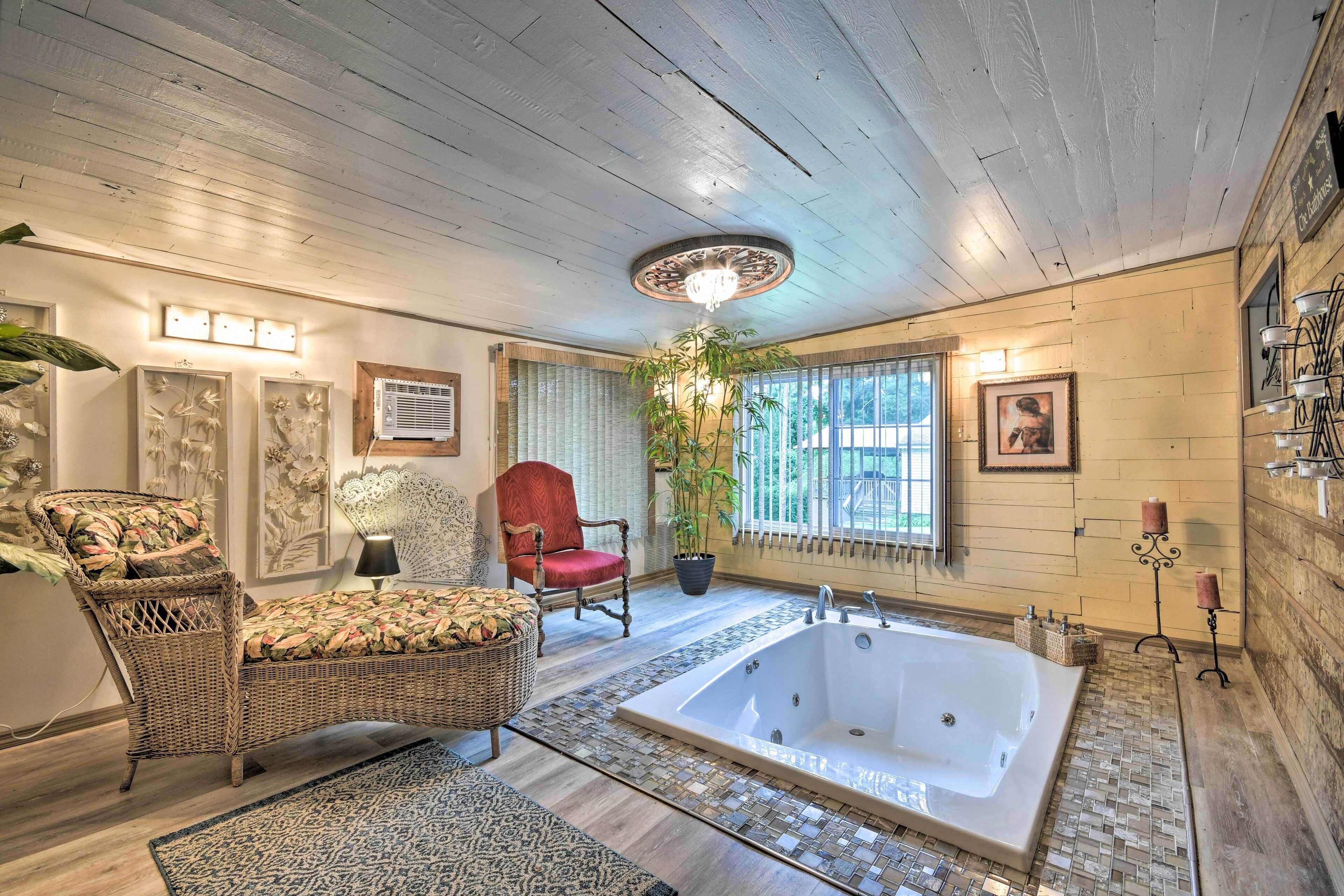 A spacious bathroom with a large bathtub, wicker furniture, and a potted plant.