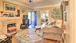 A cozy living room with a fireplace, a ceiling fan, and a large round rug. - Walk to Midwestern State: Wichita Falls Cottage! (Wichita Falls)