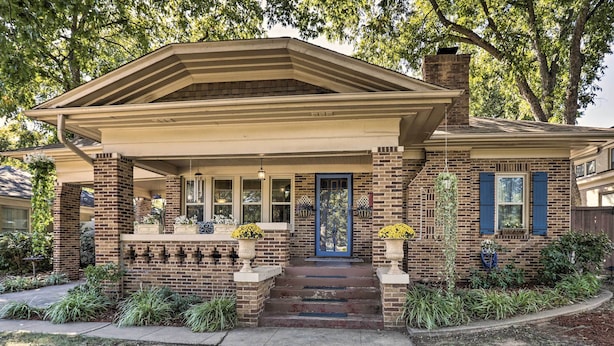 A two-story house with a brick facade, a blue front door, and a covered porch with steps leading to the entrance. - Walk to Midwestern State: Wichita Falls Cottage! (Wichita Falls)