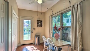 A dining area with a table and chairs, a window with curtains, a ceiling fan, and a trash can. - Walk to Midwestern State: Wichita Falls Cottage! (Wichita Falls)