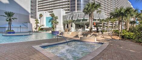 A hotel with a swimming pool, palm trees, and a modern building facade.