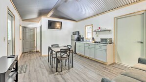 A compact living space with a dining area, kitchenette, and a ceiling fan. - Tallassee Cabin w/ Forest Views Near Creek! (Tallassee)