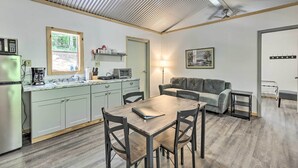 A compact kitchen with a dining area, a sofa, and a small table. - Tallassee Cabin w/ Forest Views Near Creek! (Tallassee)