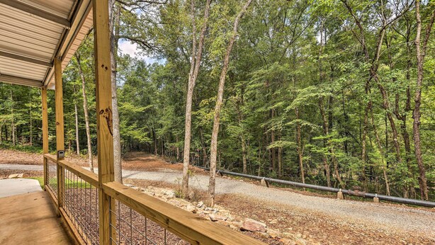 A wooden deck with a metal railing overlooking a forested area with a gravel path and a metal pipe running through it. - Tallassee Cabin w/ Forest Views Near Creek! (Tallassee)
