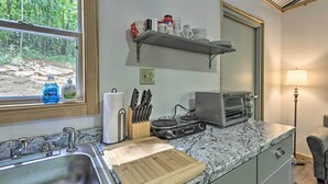 A kitchen with a granite countertop, a sink, a toaster, and a window with a view of a forest. - Tallassee Cabin w/ Forest Views Near Creek! (Tallassee)