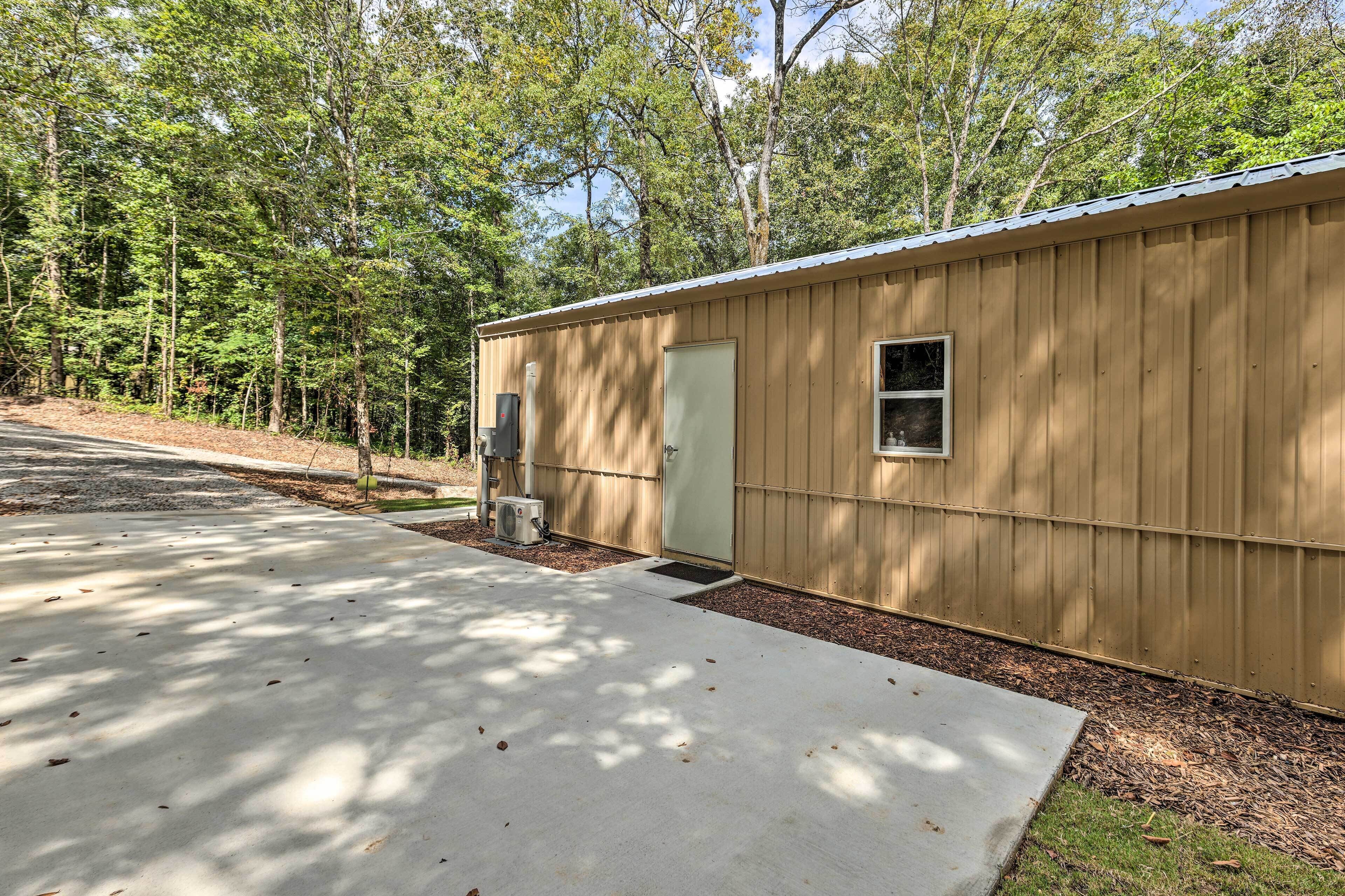 A single-story wooden building with a door and a small window, surrounded by trees.