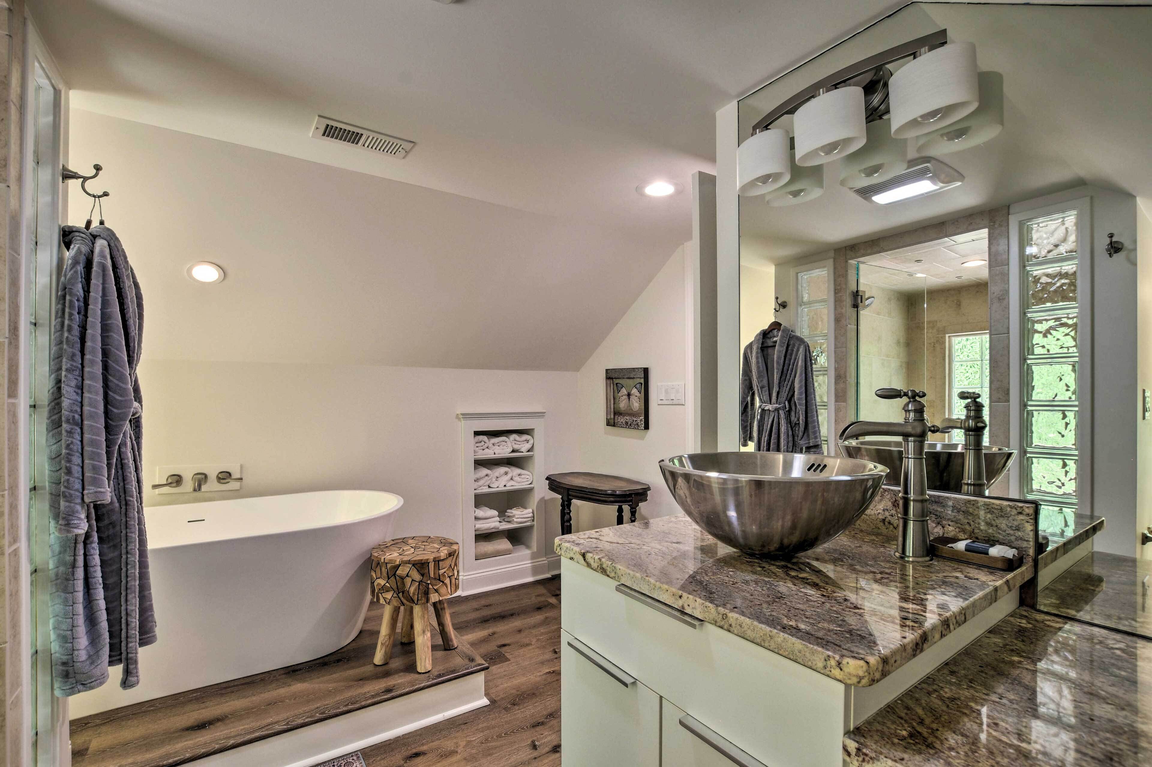 A modern bathroom with a freestanding bathtub, a large sink with a bowl, and a vanity with a mirror.