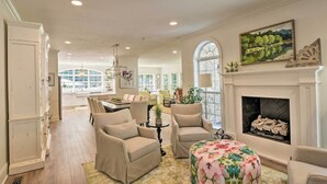 A spacious living room with a fireplace, comfortable seating, and a view through large windows.