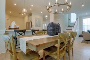 A spacious dining area with a wooden table, chairs, and a chandelier.