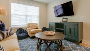 A living room with a sofa, a bean bag, a round table, a television on the wall, and a cabinet. - 3 Decks & Beach Access: Hilton Head Home (Hilton Head Island)