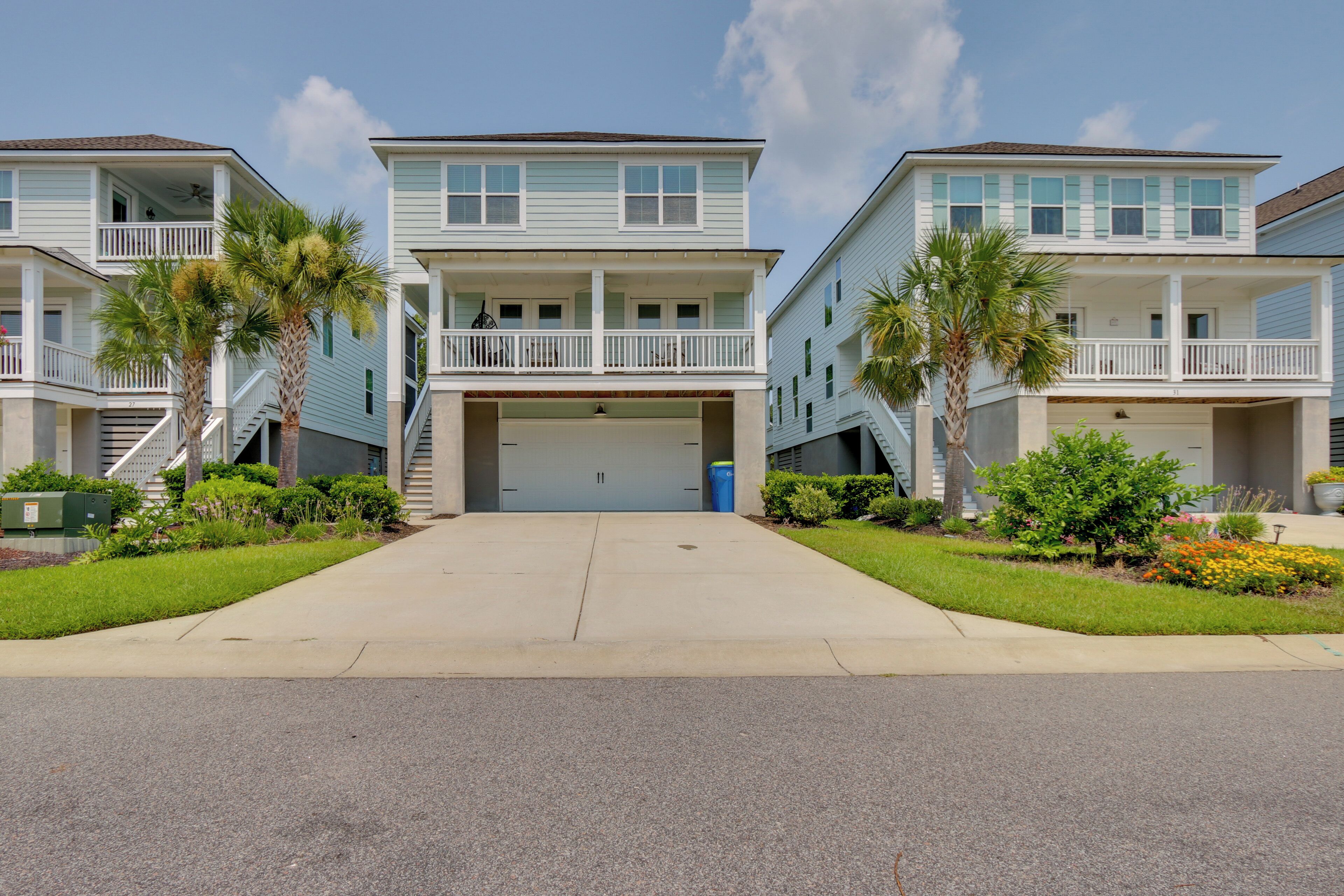 A row of two-story beachfront condominiums with balconies, a central garage, and a well-maintained lawn.