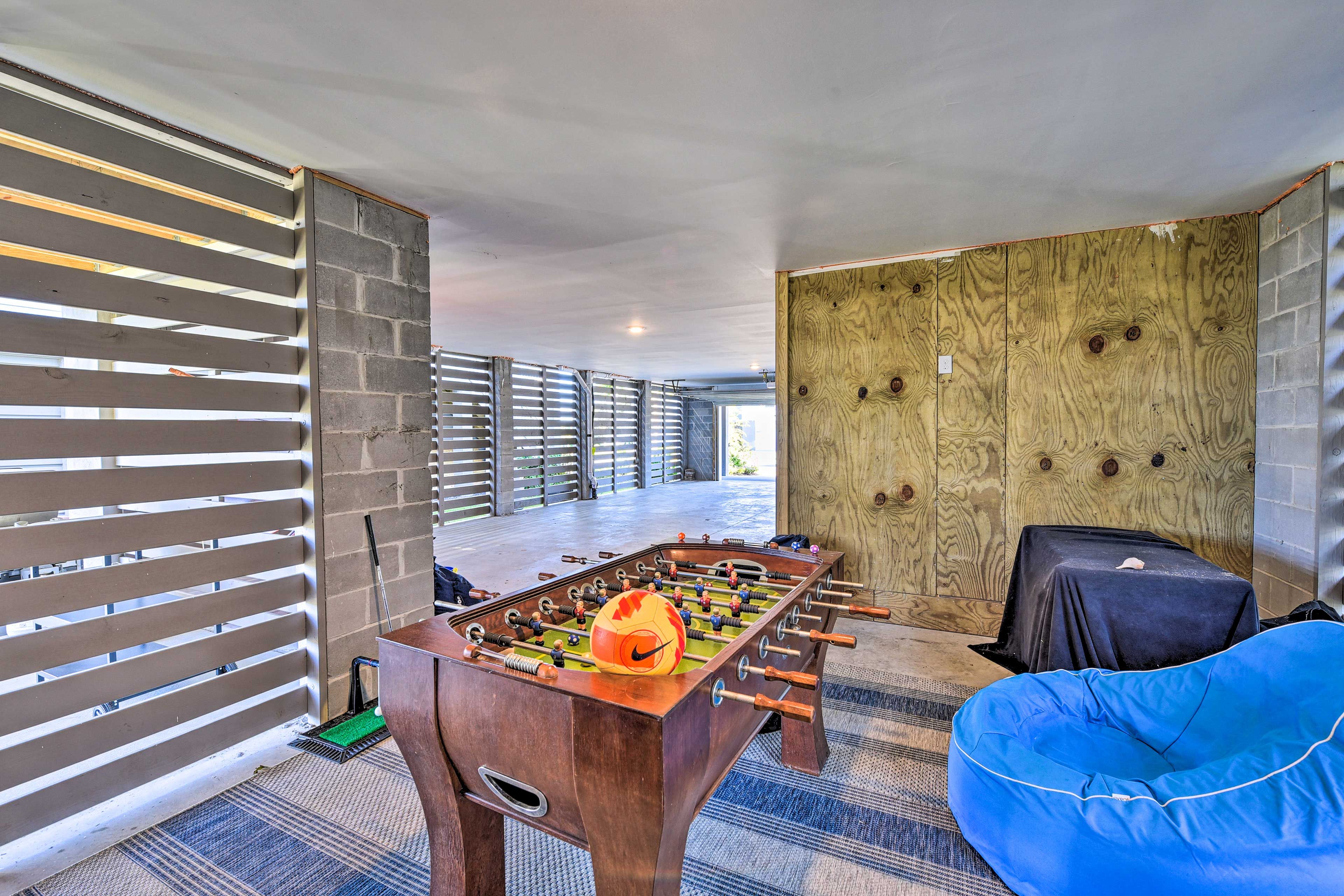 A modern room with a foosball table, a blue bean bag, and a large wooden wall.