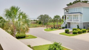 A two-story house with a balcony, surrounded by well-maintained landscaping including palm trees and shrubs. - 3 Decks & Beach Access: Hilton Head Home (Hilton Head Island)