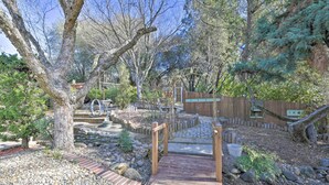 Ein Garten mit einer Holzbrücke, Steinwegen und einem Holzzaun.