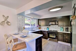 Una cocina moderna con una isla central, armarios oscuros y un amplio ventanal que proporciona luz natural.
