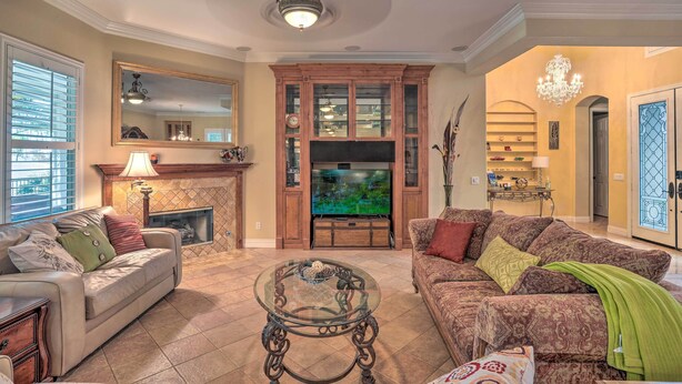A living room with a fireplace, a television, and a chandelier. - Indio Home w/ Resort Amenities, Near Festivals! (Indio)