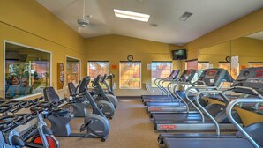 A gym with multiple treadmills and stationary bikes, large windows, and a mirror reflecting the equipment. - Indio Home w/ Resort Amenities, Near Festivals! (Indio)